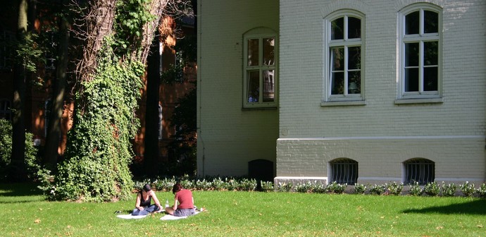 Zwei Personen sitzen auf der Sommerwiese und lesen.