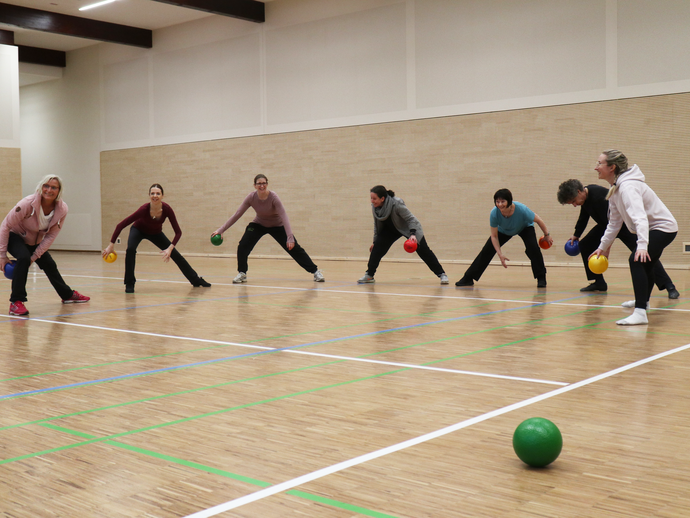 Bewegungstherapeutinnen und Therapeuten bei einer Ballübung (vergrößerte Bildansicht wird geöffnet)