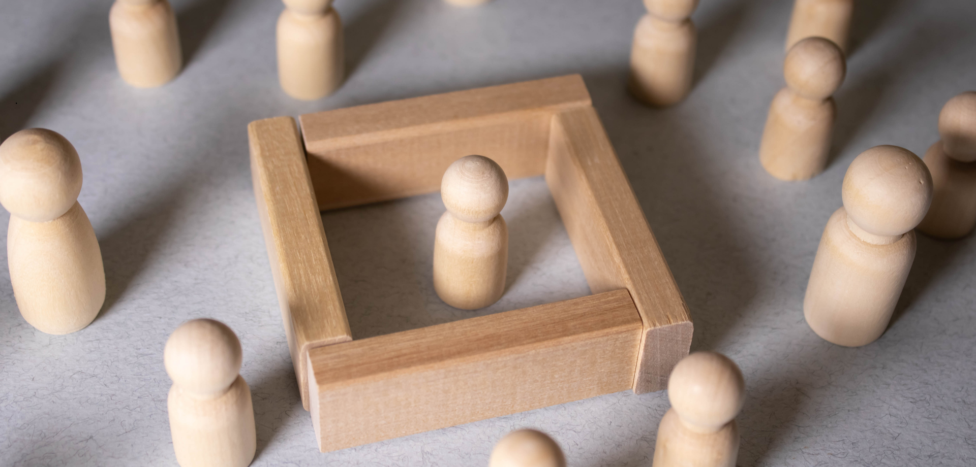 Spielfiguren in einem Spielfeld, ein Püppchen befindet sich allein in einem Kasten