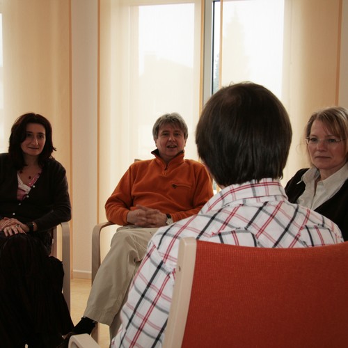 Zwei Frauen und zwei Männer sitzen in einem kleine kreis. Ein Mann richtet das Wort an einen anderen Mann