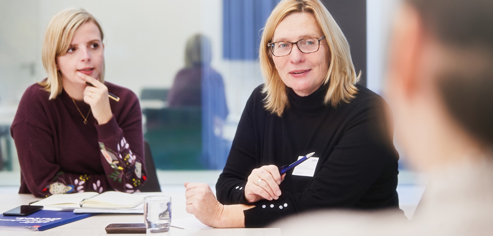 Eine Ausbilderin wendet sich im Tischgespräch an Auszubildende
