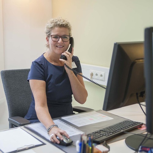 Eine junge Frau telefoniert und schaut dabei freundlich in die Kamera