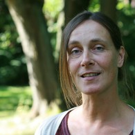 Eine Frau steht vor einem Baum und schaut interessiert in die Kamera Eine Frau steht vor einem Baum und schaut interessiert in die Kamera