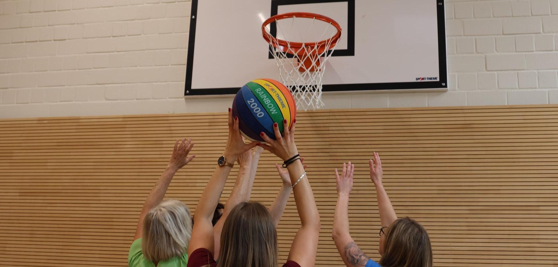Frauen werfen einen Ball in einen BASKETBALLKORB
