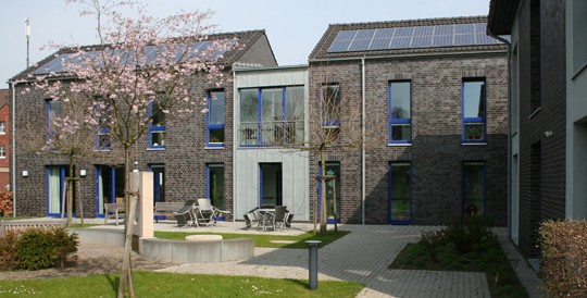 Der Innenhof der Tagesklinik Brackel mit moderner, grauer Klinkerfassade, davor ein blühender Kirschbaum