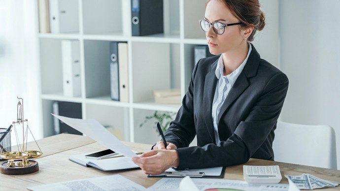 Eine Frau sitzt bei Büroarbeit am Schreibtisch und hat ihren Computer im Blick. Eine Frau sitzt bei Büroarbeit am Schreibtisch und hat ihren Computer im Blick.