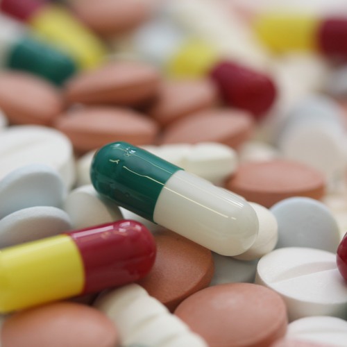 Zahlreiche Tabletten unterschiedlicher Farbe liegen bunt durcheinander auf einem Tisch