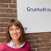 Dr. Andrea Rawert steht vor einer Wand und lächelt in die Kamera