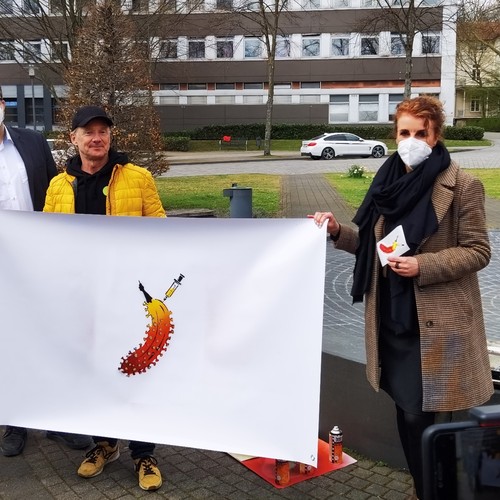 Drei Männer und eine Frau halten ein Plakat mit einer stilisierten Banane