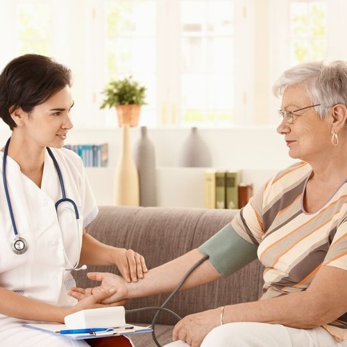 Psychiatrische PflegeEine Krankenschwester misst den Blutdruck einer älteren Dame. Beide Frauen schauen sich an