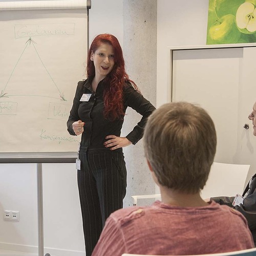 Eine Therapeutin informiert Angehörige im Gruppengespräch.
