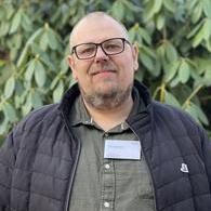 Ein Mann mit Brille schaut freundlich in die Kamera