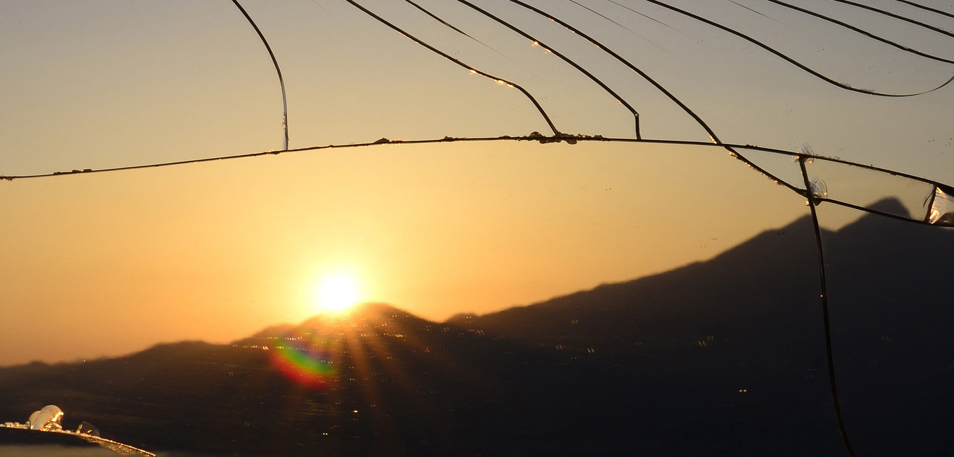 Blick auf die untergehende Sonne durch ein zerbrochenes Fenster