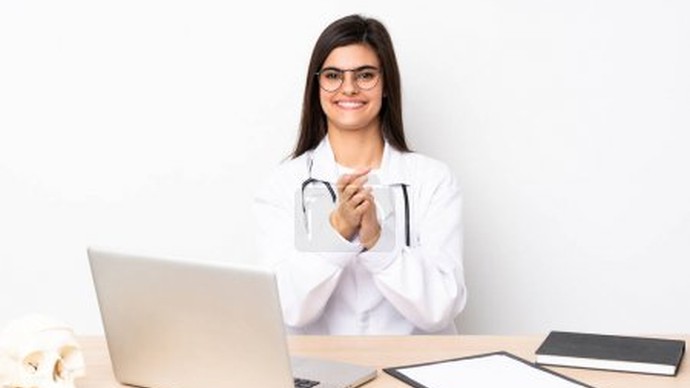 Eine medizinische Fachangestellte sitzt am Schreibtisch, vor ihr diverses Unterlagen